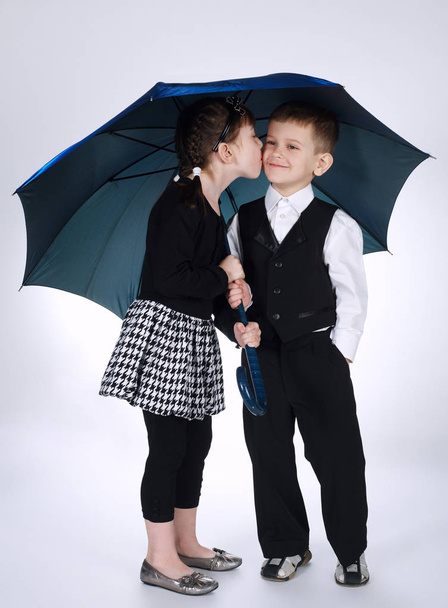 素敵な男の子と女の子の傘の下で立っています。 - 写真・画像