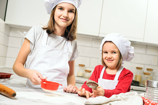Sisters making dough in white kitchen - Photo, image
