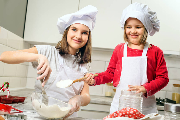 Sisters making dough in white kitchen - Fotografie, Obrázek
