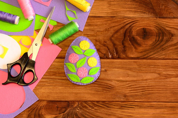 Voelde Easter egg, naaien materialen en gereedschappen op houten achtergrond met kopie lege ruimte voor tekst. Heldere ei ambachten gemaakt van vilt en versierd met bloemen. Pasen crafts achtergrond. Bovenaanzicht - Foto, afbeelding