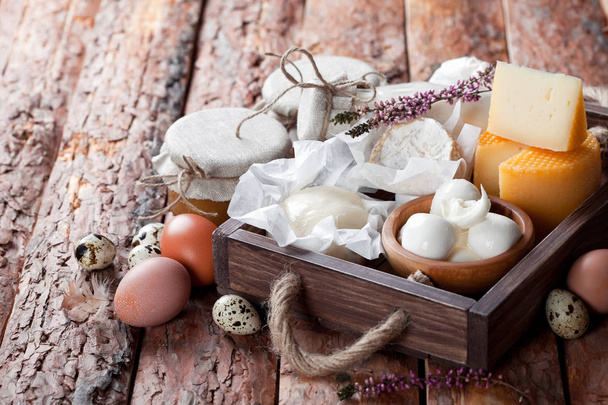 Taze süt ve süt ürünleri: peynir, tereyağı, süt ve yumurta ahşap kutusunda - Fotoğraf, Görsel
