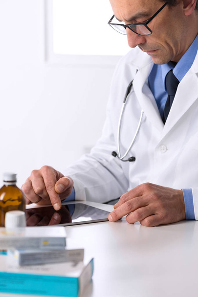 male doctor with stethoscope at desk using tablet - Fotografie, Obrázek