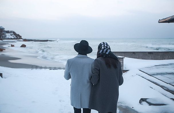 couple in winter clothes walking on seacoast  - Photo, Image