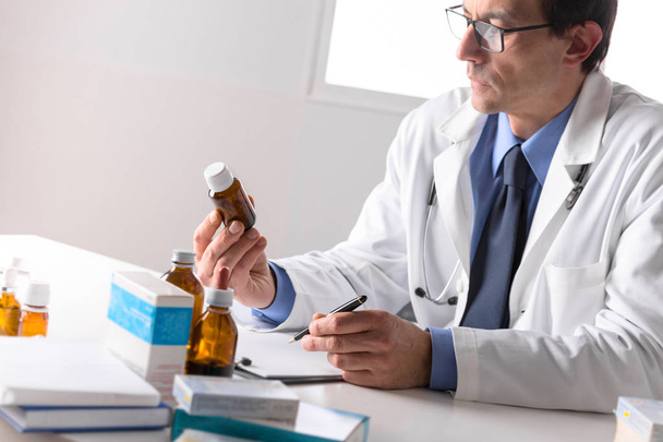 male pharmacist sat at desk reading notes - Photo, Image