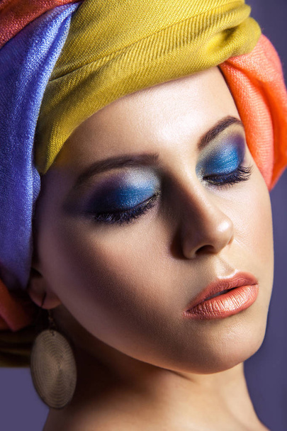 Красива жінка з кольоровим головним убором і синім макіяжем
. - Фото, зображення