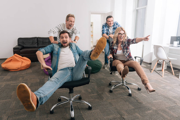 Uomini allegri positivi che spingono sedie da ufficio
 - Foto, immagini