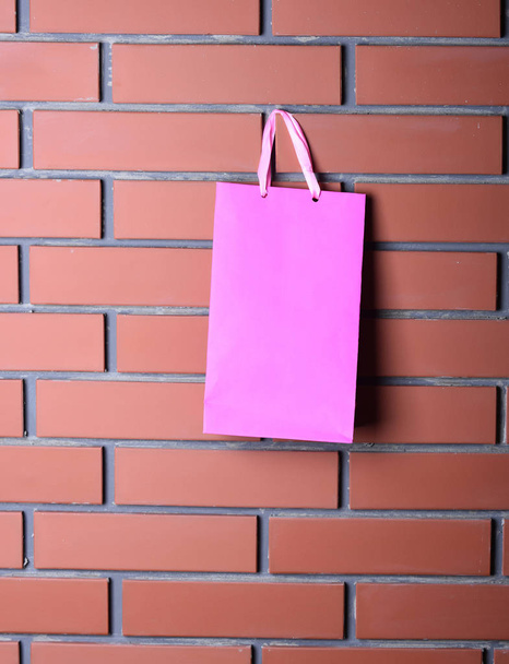 pink shopping bag on brown brick wall, copy space - Photo, image
