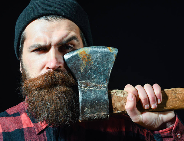 Handsome bearded man in hat holds axe on black background - Foto, Imagen