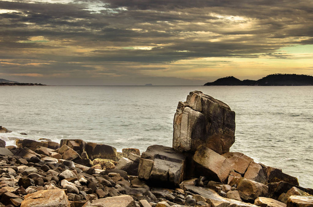 Gran piedra puntiaguda entre las formaciones rocosas junto al mar
 - Foto, Imagen