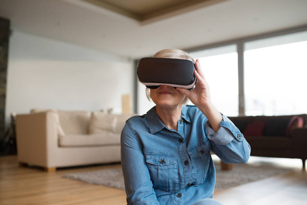 Senior woman wearing virtual reality goggles at home - Fotografie, Obrázek