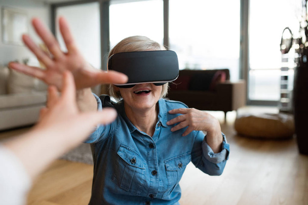 Senior woman wearing virtual reality goggles at home - Фото, зображення