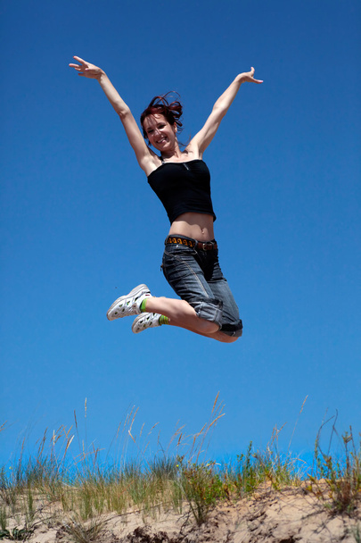 dziewczyna skoki na tle niebieskiego nieba - Zdjęcie, obraz
