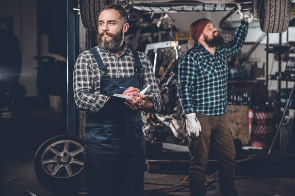 Mannen repareren auto in een garage. - Foto, afbeelding