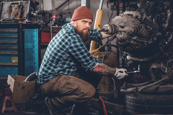 Bearded man repairing car engine - 写真・画像