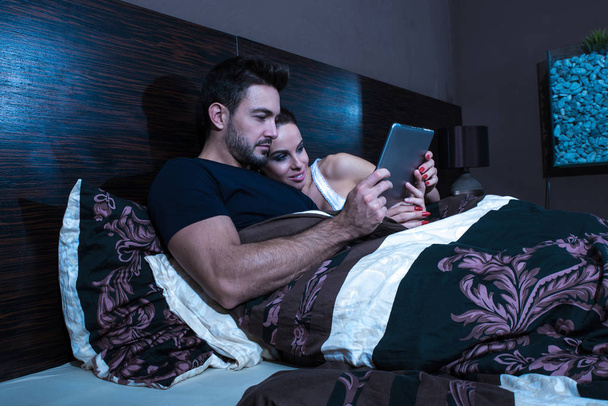 Beautiful young couple using a Tablet PC in Bed - Fotografie, Obrázek