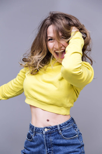 Young attractive girl in yellow sweatshirt dancing - Photo, Image