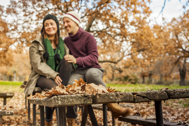 Leaves over a wood table in the park with couple at the backgrou - Foto, imagen