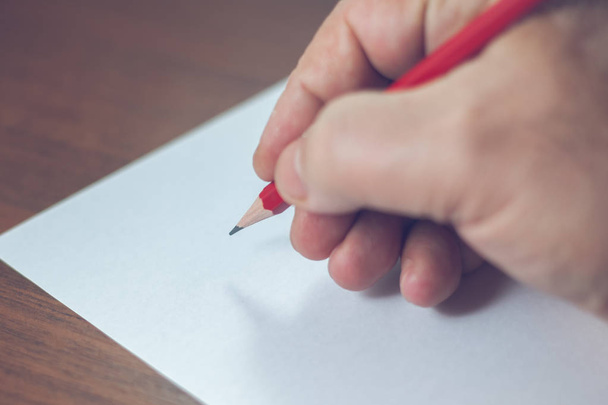 A close photo of a persons writing a letter with a pencil - Fotó, kép