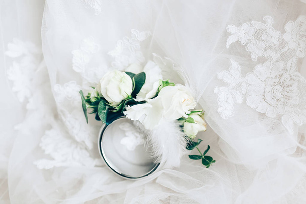 Красивая бутоньерка с кольцом на белом свадебном платье, крупным планом
 - Фото, изображение