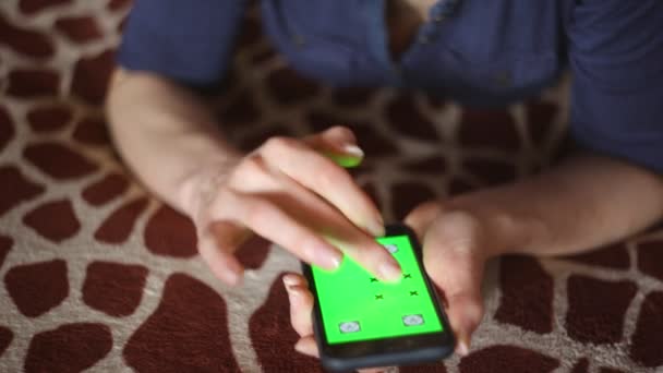 Молода жінка грає зі смартфоном вдома на постільній білизні жирафа зелений екран тільки готові руки
 - Кадри, відео