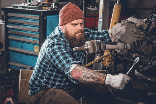 Человек ремонтирует двигатель автомобиля в гараже
 - Фото, изображение