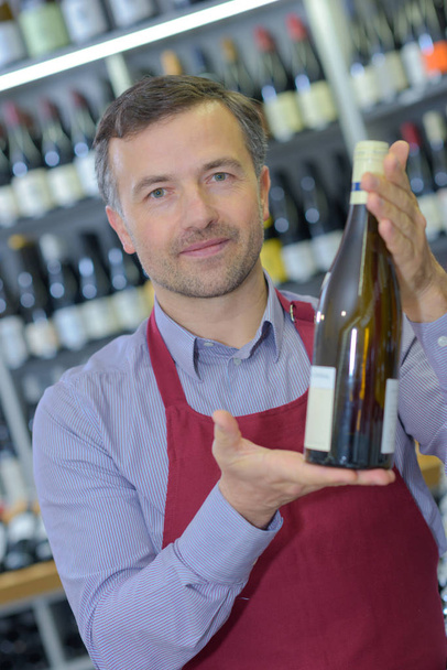 Salesman holding bottle of white wine - 写真・画像