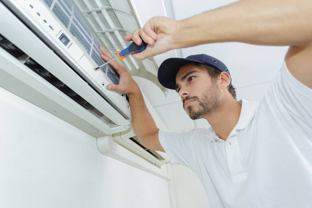 portrait of mid-adult male technician repairing air conditioner - Foto, Bild