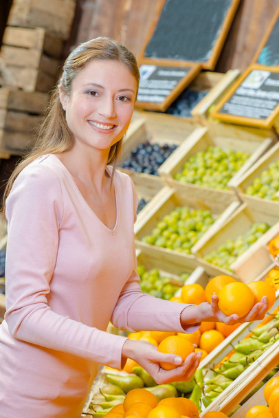 Lady choosing oranges in grocers - Valokuva, kuva