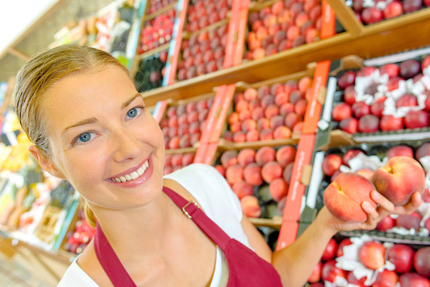 Shop assistant holding peaches - Фото, зображення