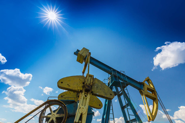 Эксплуатация нефтегазовой скважины на европейском нефтяном месторождении, профилированная на голубом небе с кучевыми облаками
 - Фото, изображение