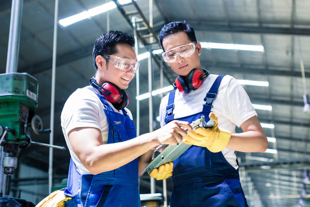 dos trabajadores industriales inspeccionando la pieza de trabajo
 - Foto, Imagen