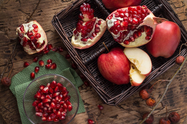 Pieces of red pomegranate and Apple in wooden basket - Photo, image