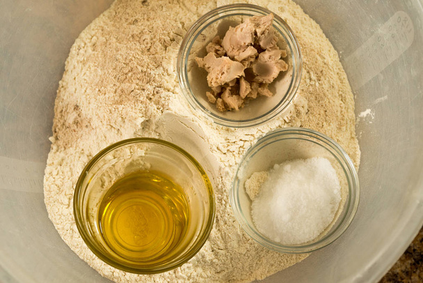 Aceite, azúcar y pasta para hornear en un tazón de preparación en un montón de harina en un tazón grande para mezclar
 - Foto, Imagen