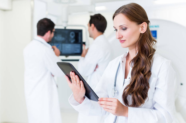 Médico com colegas em pé no hospital na máquina de TC
 - Foto, Imagem