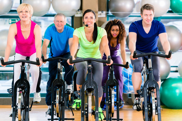 Fitness group of men and women spinning of bike in gym - Zdjęcie, obraz