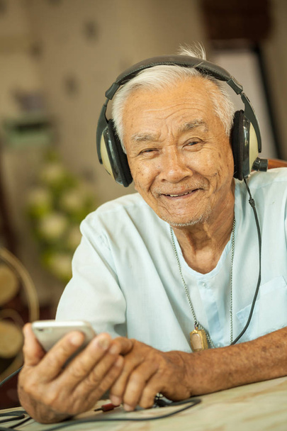 Heureux asiatique senior homme écouteurs écoute musique à la maison
 - Photo, image