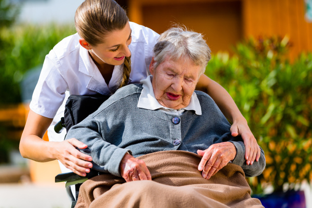 Mujer mayor en residencia de ancianos con enfermera en el jardín
 - Foto, imagen