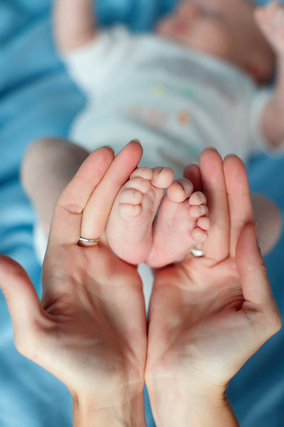 Τα χέρια της μητέρας του στοργική υποστήριξη απαλά τα πόδια το μωρό - Φωτογραφία, εικόνα