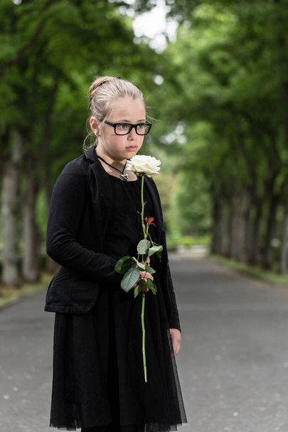 girl with white rose mourning deceased on graveyard - Photo, Image