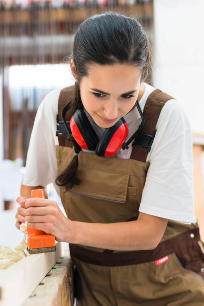 Carpintero mujer trabajando con cepilladora
 - Foto, Imagen