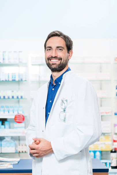 Apothecary in pharmacy standing at shelf - Photo, image