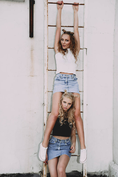 lifestyle and people concept: Fashion portrait of two stylish girls best friends wearing jeans skirts, outdoors on the roof. Happy summer time for fun. Concept of 90s. Retouched photo - Photo, Image