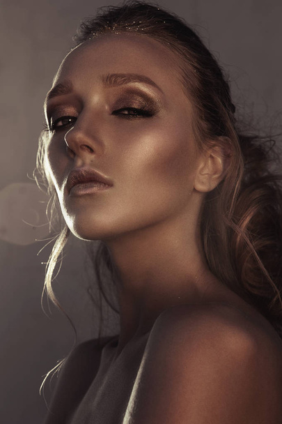 Glamour portrait of young fashion woman face with bright evening golden make up for party and tanned skin. Warm toning. Retouched close up portrait - Photo, Image