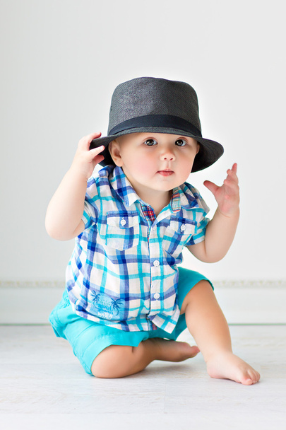 Cute baby sitting on the floor in a hat - Фото, изображение