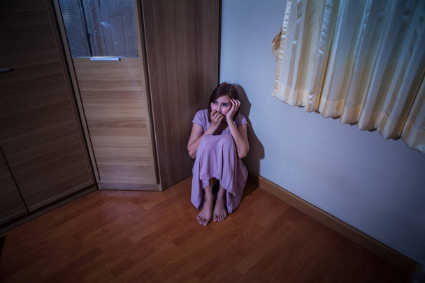 部屋の隅に座っている怖がっている虐待を受ける女性 - 写真・画像