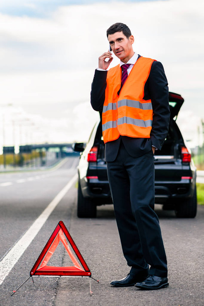 Man with car breakdown erecting warning triangle - Фото, зображення