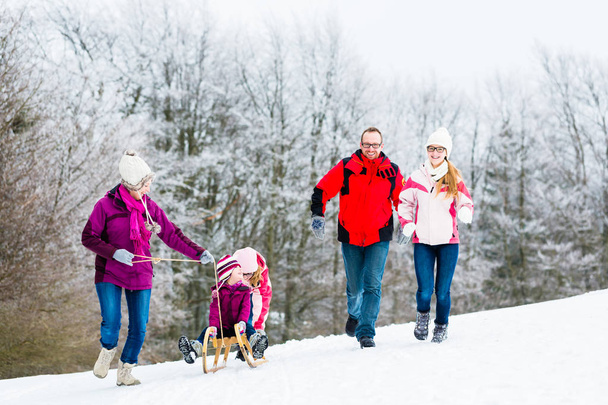 雪の中冬の散歩をしている子供連れの家族 - 写真・画像