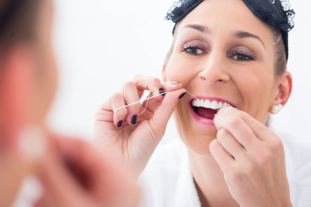 Frau putzt Zähne mit Zahnseide - Foto, Bild