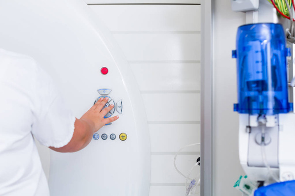 Krankenschwester drückt im Krankenhaus Knopf an CT-Maschine - Foto, Bild