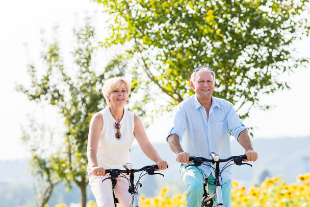 Senior couple, woman and man, riding their bikes - Фото, зображення